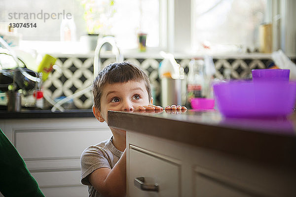 Junge versteckt sich und spielt zu Hause in der Küche
