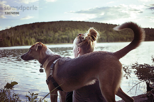 Rückansicht von Frau und Hund gegen See und Berg