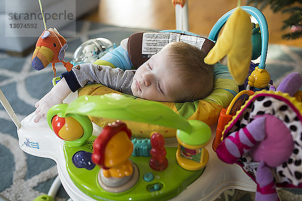 Hochwinkelaufnahme eines zu Hause in einer Gehhilfe schlafenden Jungen