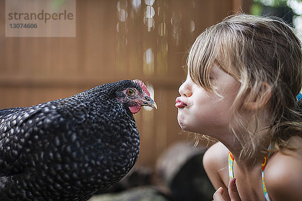 Glückliches Mädchen kräuselt Henne im Freien