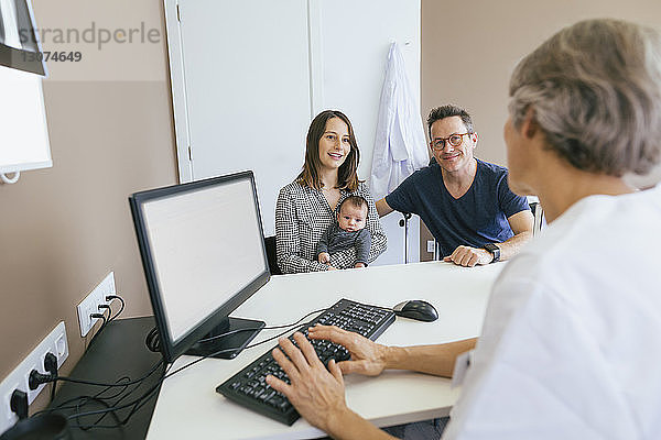 Glückliche Familie bespricht sich mit Arzt in medizinischer Klinik