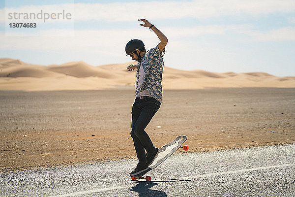 Mann fährt bei Sonnenschein Skateboard auf der Straße