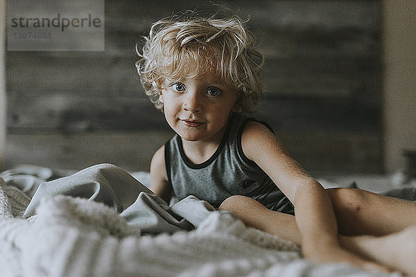 Porträt eines lächelnden Jungen  der sich auf dem Bett ausruht