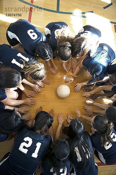 Hochwinkelansicht einer Volleyball-Mädchenmannschaft  die auf dem Boden kauert