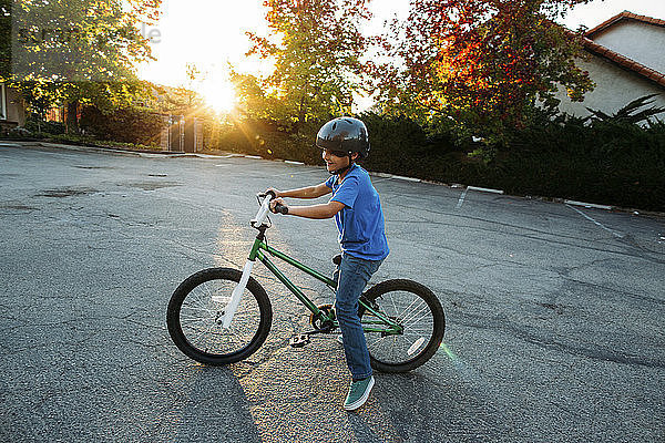 Junge mit Fahrradhelm beim Fahrradfahren bei Sonnenuntergang