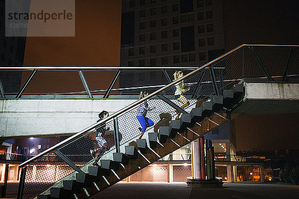 Niedrigwinkelansicht von Athletinnen  die nachts auf den Stufen einer Brücke laufen