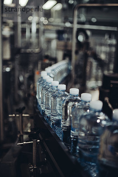 Nahaufnahme von Wasserflaschen in Reihe auf einem Förderband in der Fabrik