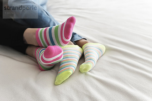 Niedriger Teil eines lesbischen Paares trägt bunte Socken  während es sich zu Hause im Bett entspannt