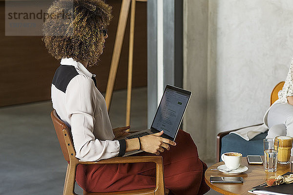 Seitenansicht einer Geschäftsfrau mit Laptop in der Hotellobby