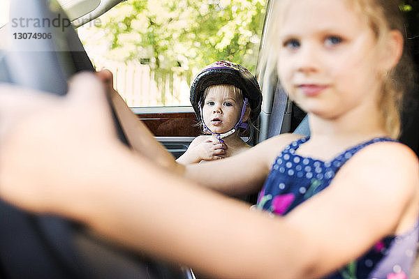 Porträt eines süßen Jungen  der mit seiner Schwester im Auto sitzt