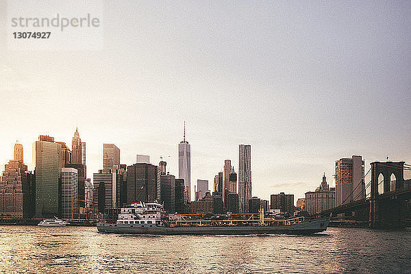 Stadtsilhouette und Brooklyn Bridge am East River in der Abenddämmerung