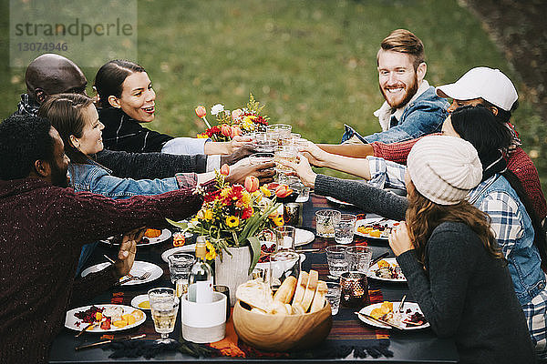 Glückliche Freunde trinken Wein  während sie im Hinterhof am Tisch sitzen