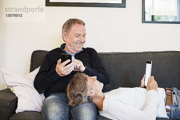 Glückliches älteres Ehepaar mit Tablet-Computer auf dem Sofa