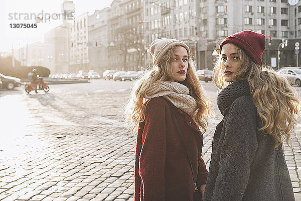 Porträt von Schwestern  die im Winter auf der Straße der Stadt stehen