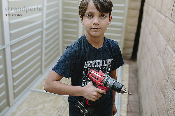 Porträt eines Jungen  der eine Übung hält  während er zu Hause an der Wand steht