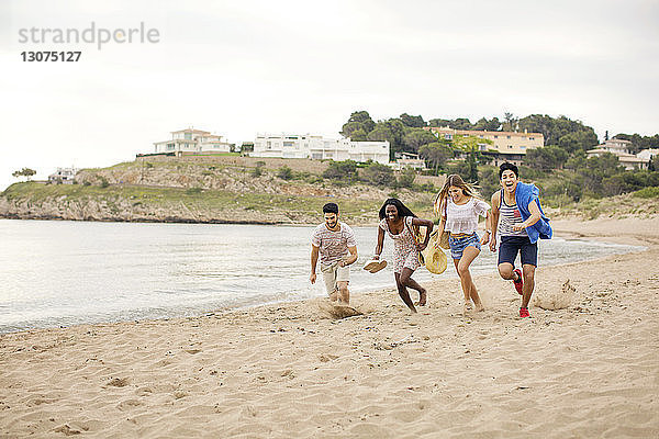 Spielerische Freunde  die im Urlaub am Strand an Land laufen