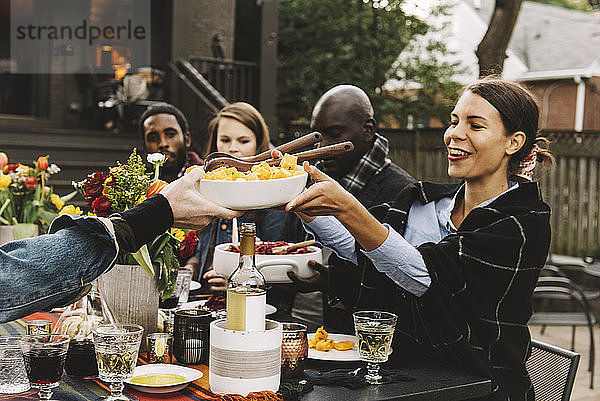 Freunde genießen das Essen  während sie im Hinterhof am Tisch sitzen