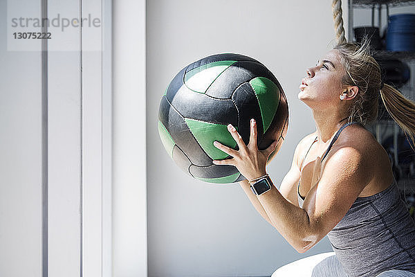 Entschlossene Sportlerin trainiert mit Medizinball in Crossfit-Turnhalle