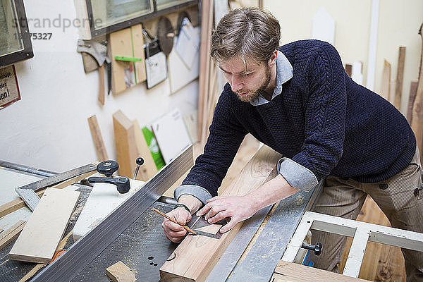 Schreiner beim Vermessen von Holzbohlen in der Werkstatt