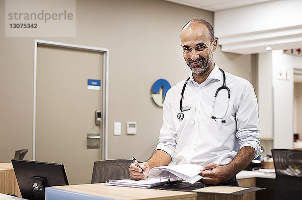 Porträt eines Arztes  der während seiner Arbeit im Krankenhaus Berichte erstellt