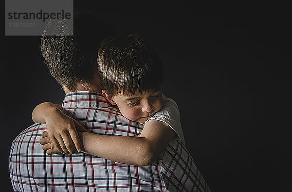 Rückansicht eines Mannes mit Sohn an der Wand stehend