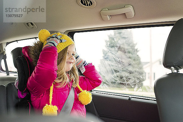 Glückliches Mädchen in warmer Kleidung im Auto unterwegs