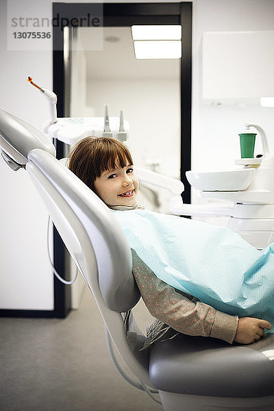 Porträt eines lächelnden Mädchens  das in der Klinik auf einem Zahnarztstuhl sitzt