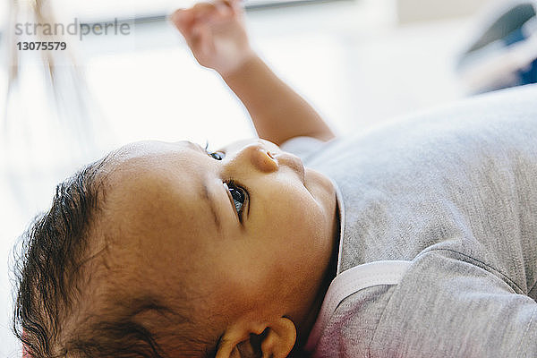 Nahaufnahme eines kleinen Jungen  der wegschaut  während er zu Hause auf dem Boden liegt