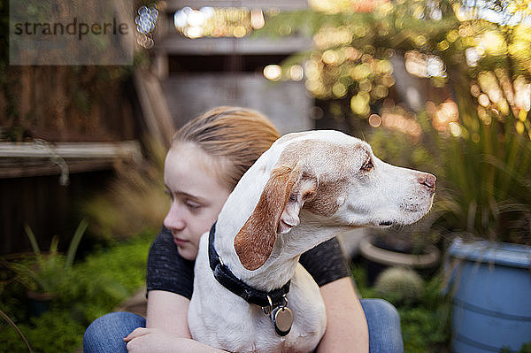 Mädchen umarmt Hund im Hinterhof