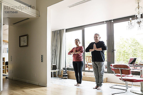 Älteres Ehepaar  das zu Hause Yoga praktiziert  in voller Länge