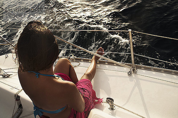 Hochwinkelaufnahme einer Frau  die bei Sonnenuntergang in einem Boot auf dem Meer sitzt