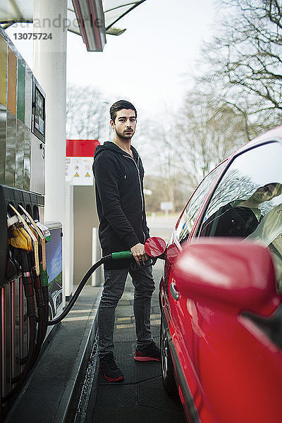 Porträt eines Mannes beim Tanken eines Autos an einer Tankstelle