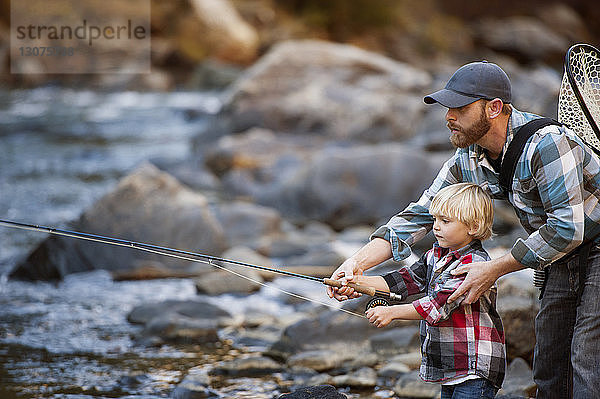 Vater fischt mit dem Sohn am Fluss im Wald