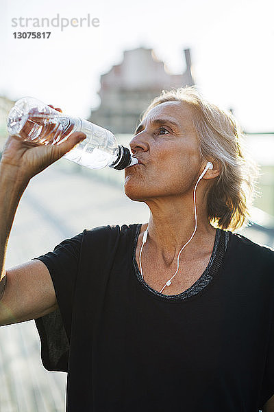 Frau trinkt Wasser beim Musikhören