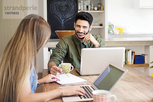 Glückliches Paar diskutiert  während es zu Hause Laptops benutzt