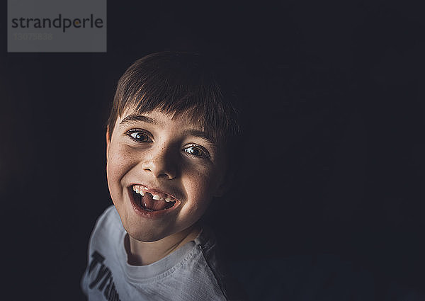Hochwinkelporträt eines glücklichen Jungen vor schwarzem Hintergrund