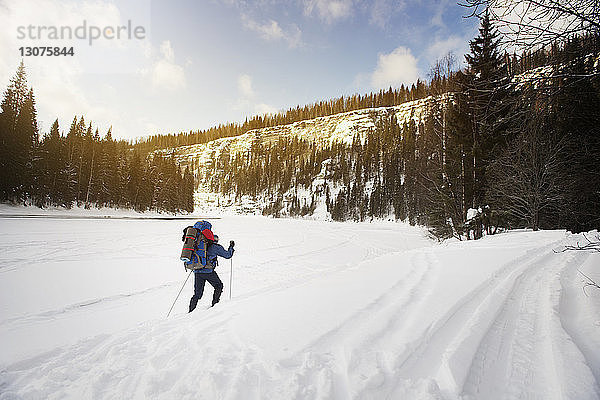 Rückansicht eines Wanderers  der auf schneebedeckter Landschaft wandert