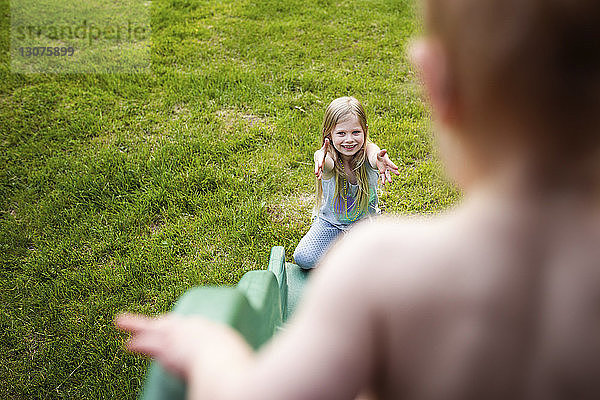 Hochwinkelansicht von Geschwistern  die auf einer Rutsche auf dem Spielplatz spielen