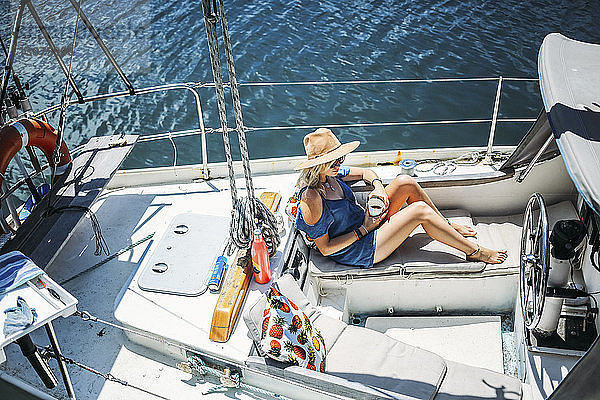 Hochwinkelaufnahme einer Frau  die sich auf einem Segelboot auf See entspannt