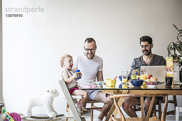 Väter spielen mit der Tochter beim Frühstück am Tisch an der Wand