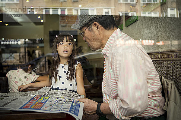 Mädchen sieht Großvater an  während sie im Restaurant sitzt  durch Glas gesehen
