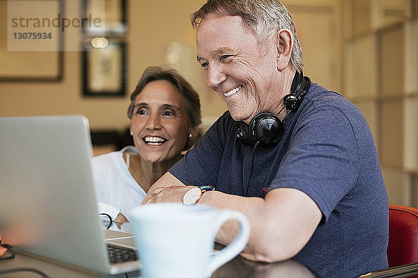 Glückliches älteres Ehepaar mit Laptop zu Hause