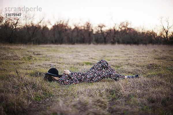 Frau in voller Länge entspannt sich auf Grasfeld