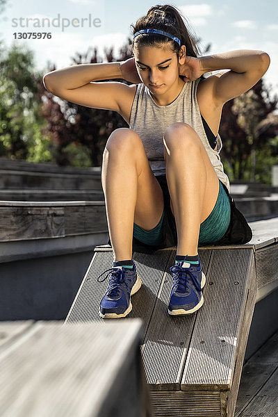 Sportlerin  die beim Training auf einem Holzsitz nach unten schaut