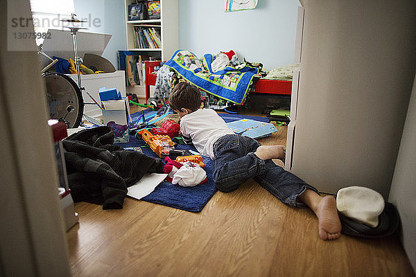 Rückansicht eines Jungen  der mit Spielzeug spielt  während er im Schlafzimmer liegt