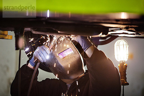 Mechanisches Schweißen unter dem Auto in einer Autowerkstatt