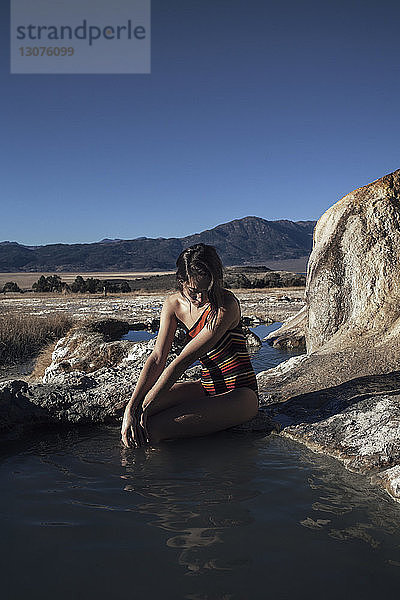 Frau sitzt auf Felsen und entspannt sich in Bridgeport Hot Springs