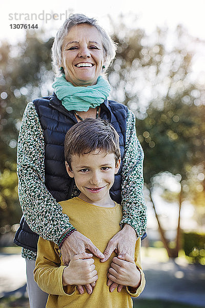 Porträt einer glücklichen älteren Frau  die mit ihrem Enkel im Park steht
