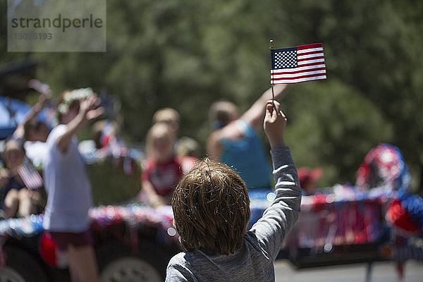 Rückansicht eines Jungen mit amerikanischer Flagge während der Feierlichkeiten zum Unabhängigkeitstag