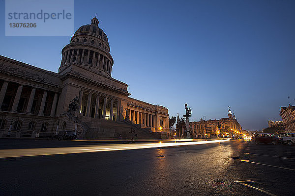 Lichtspuren auf der Stadtstraße beim Capitolo-Gebäude gegen den klaren blauen Himmel in der Abenddämmerung